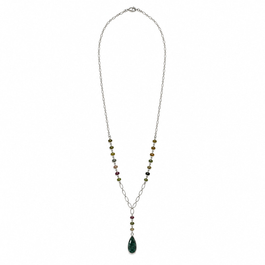 Woman in a lavender blouse wearing the long emerald and tourmaline rosary necklace outdoors