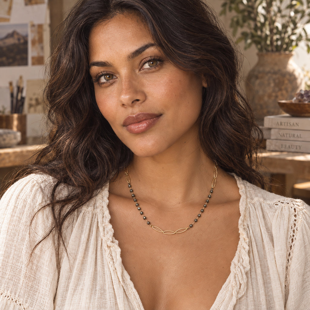 Pyrite and gold-filled marquise chain necklace laid flat, showing faceted beads and three gold links at the front