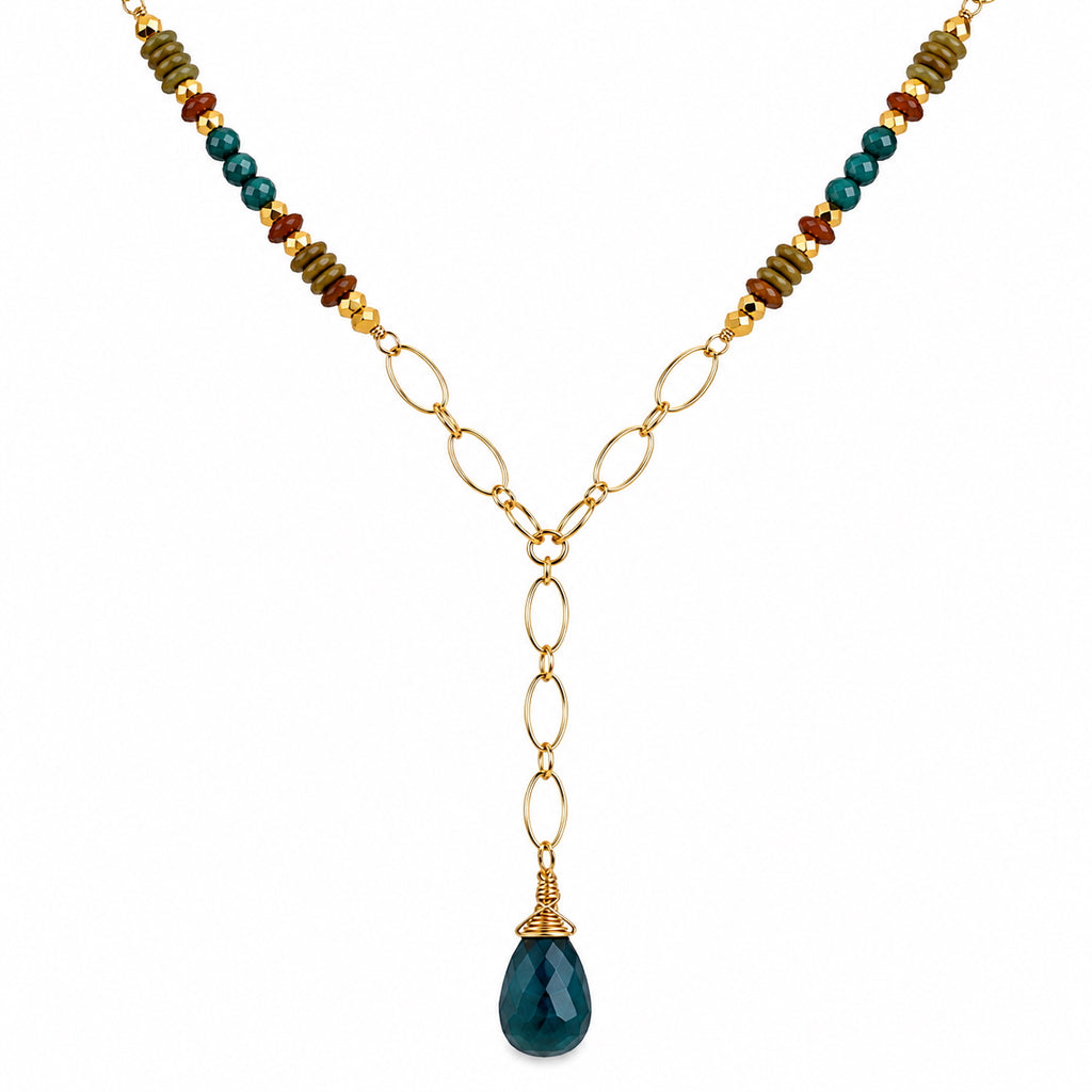 Woman wearing grandidierite Y necklace with green garnet, red garnet, and apatite beads