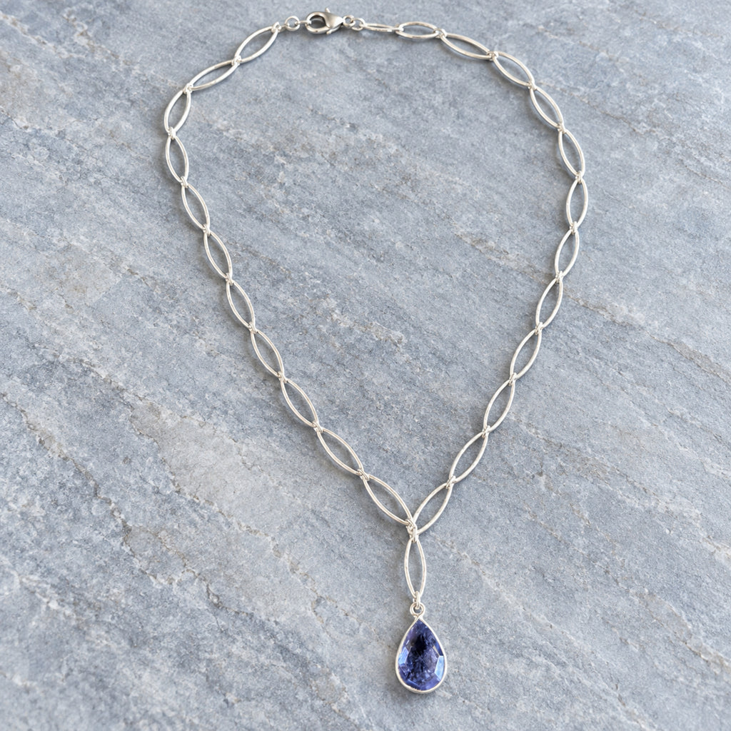 Woman wearing iolite teardrop pendant necklace on sterling silver marquise chain