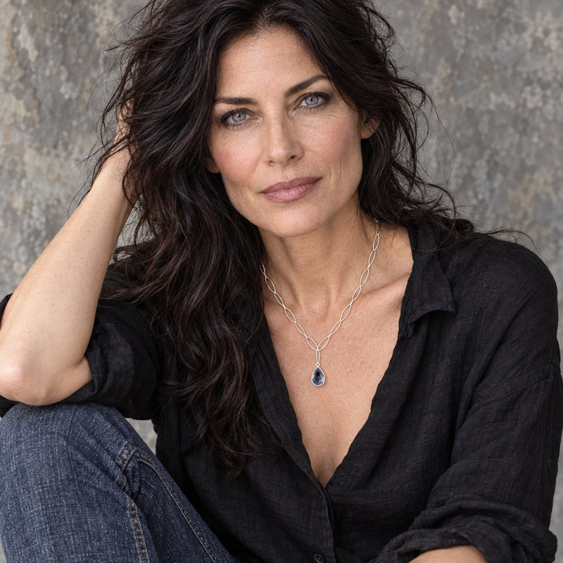 Woman wearing iolite teardrop pendant necklace on sterling silver marquise chain