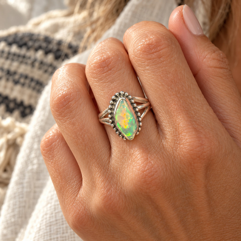 Freeform Ethiopian crystal opal ring with green and orange fire in a beaded sterling silver bezel, front view.