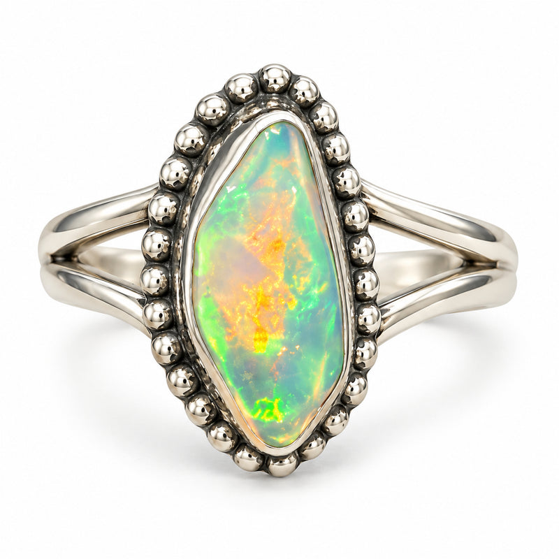 Freeform Ethiopian crystal opal ring with green and orange fire in a beaded sterling silver bezel, front view.