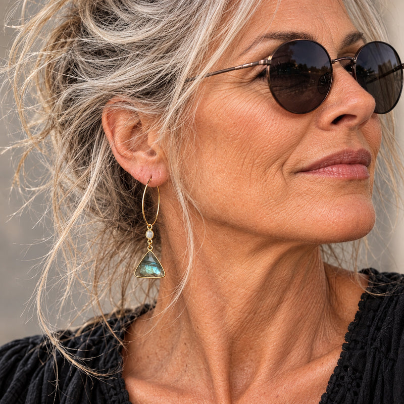 Woman wearing labradorite triangle gold-filled dangle hoop earrings with moonstone connector