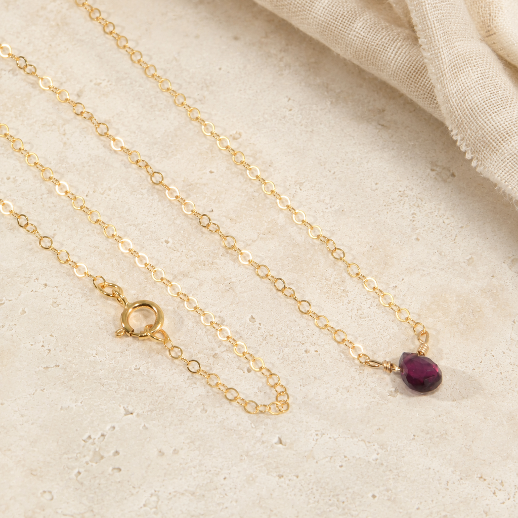 Model wearing a minimalist natural rhodolite garnet teardrop necklace on a delicate gold-filled chain