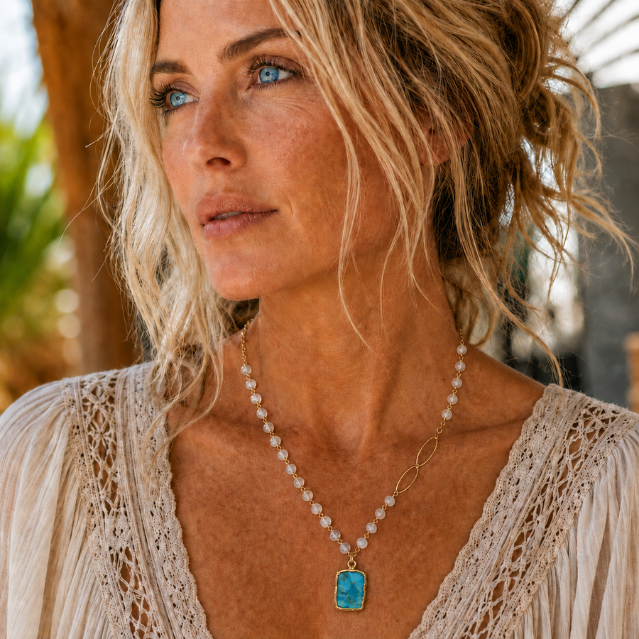 Model wearing an asymmetric natural turquoise and rainbow moonstone necklace with gold-filled chain and marquise links.