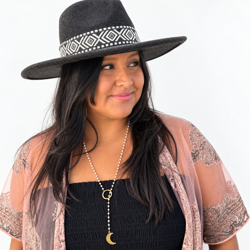 Woman in a wide-brim hat wearing the long pearl rosary crescent moon lariat necklace