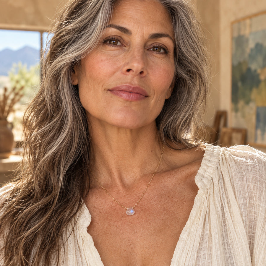 Woman wearing rainbow moonstone gold-filled solitaire necklace