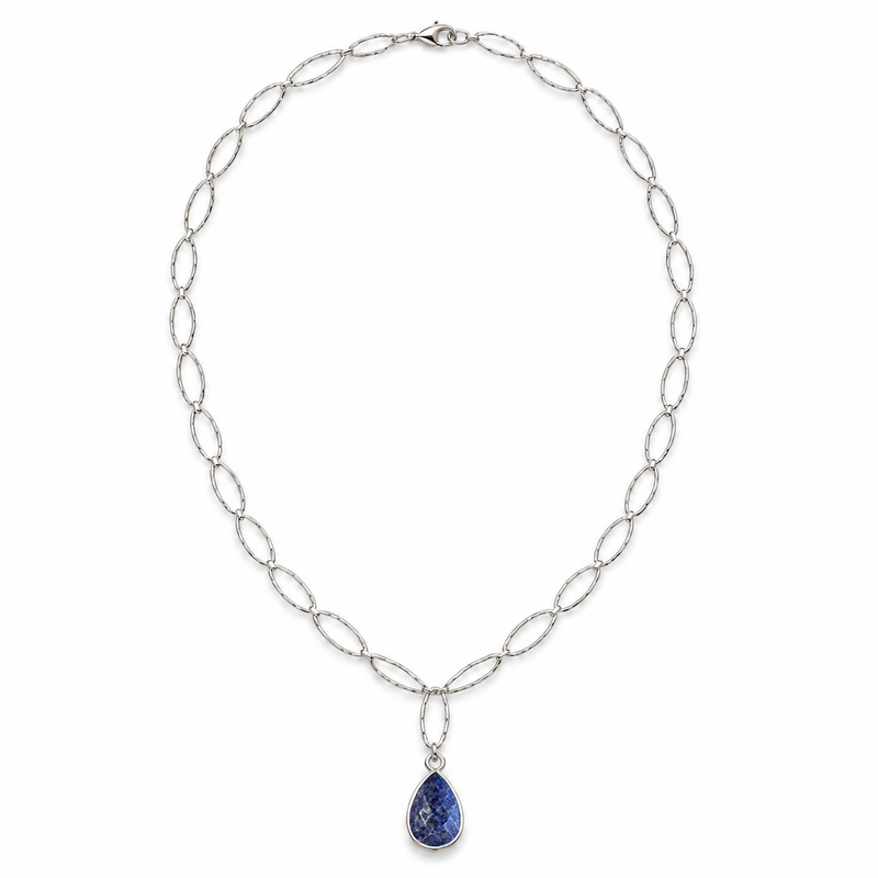 Blue sapphire teardrop pendant necklace in sterling silver laid flat on linen